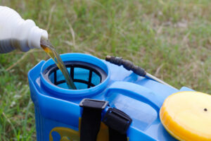 pouring herbicide water from bottle into tank sprayer